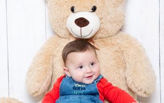 a little boy sits resting against a giant teddy bear
