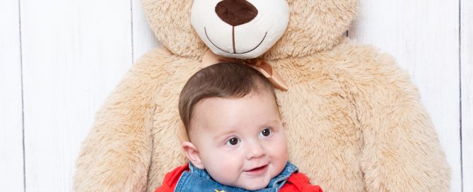 a little boy sits resting against a giant teddy bear
