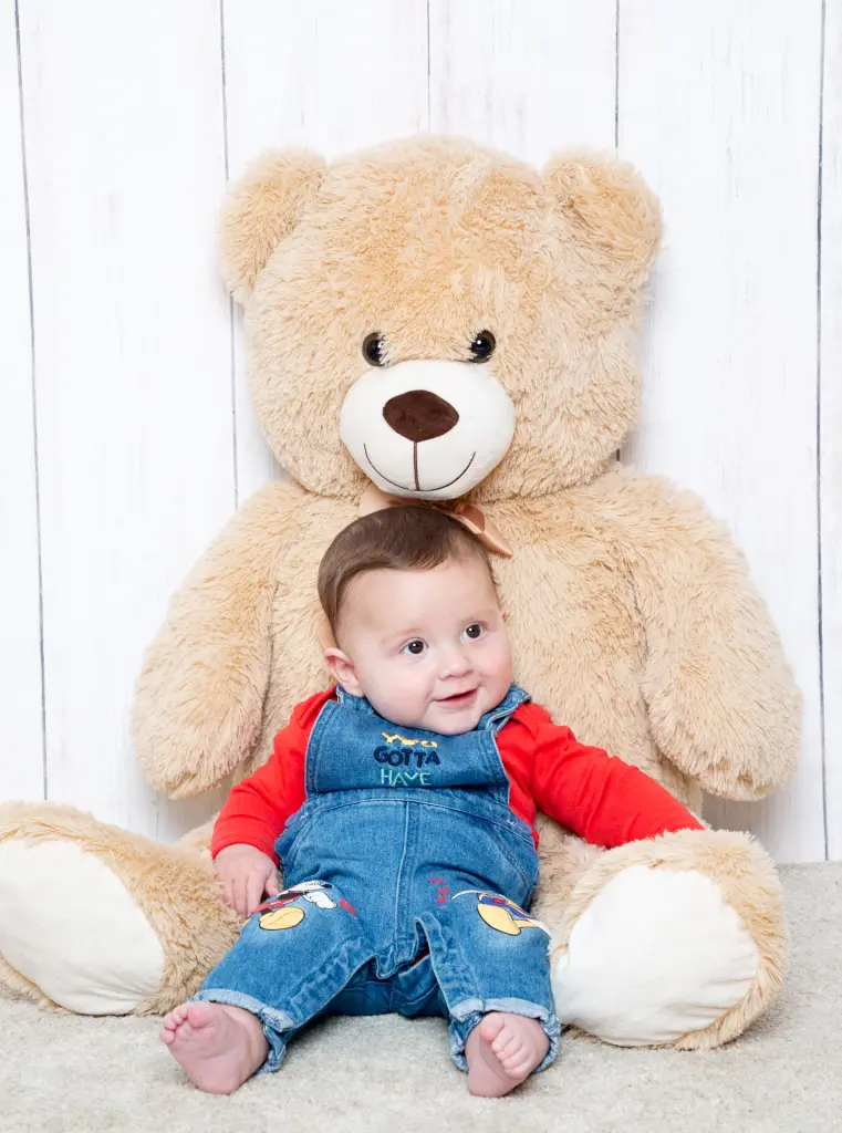 Baby Photography East Grinstead West Sussex a little boy sits resting against a giant teddy bear