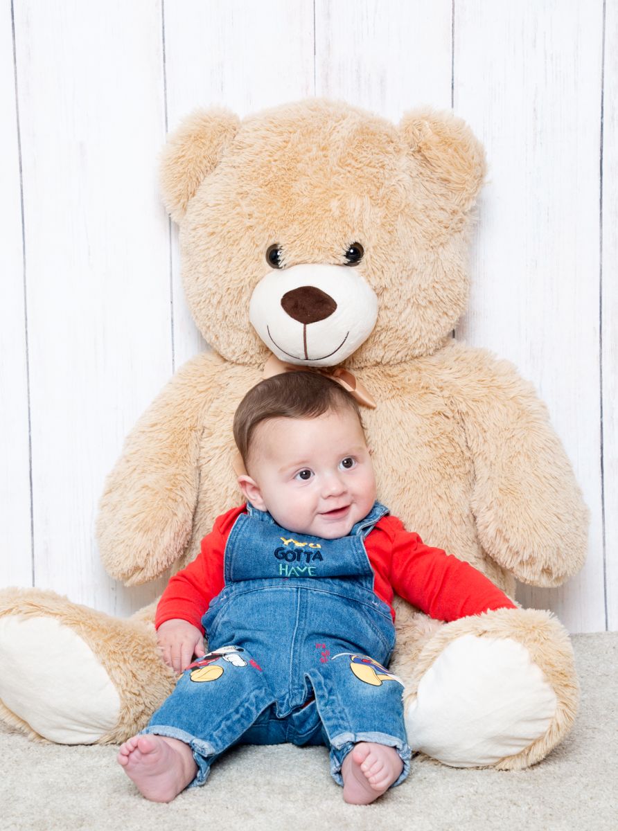 a little boy sits resting against a giant teddy bear