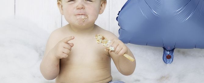 A little boy screws up his face in delight at his cake at a photo shoot