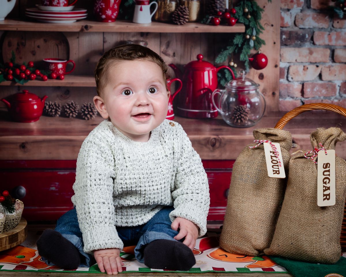 Christmas Photo Shoots West Sussex 2025 a baby sits in a christmas kitchen themed set