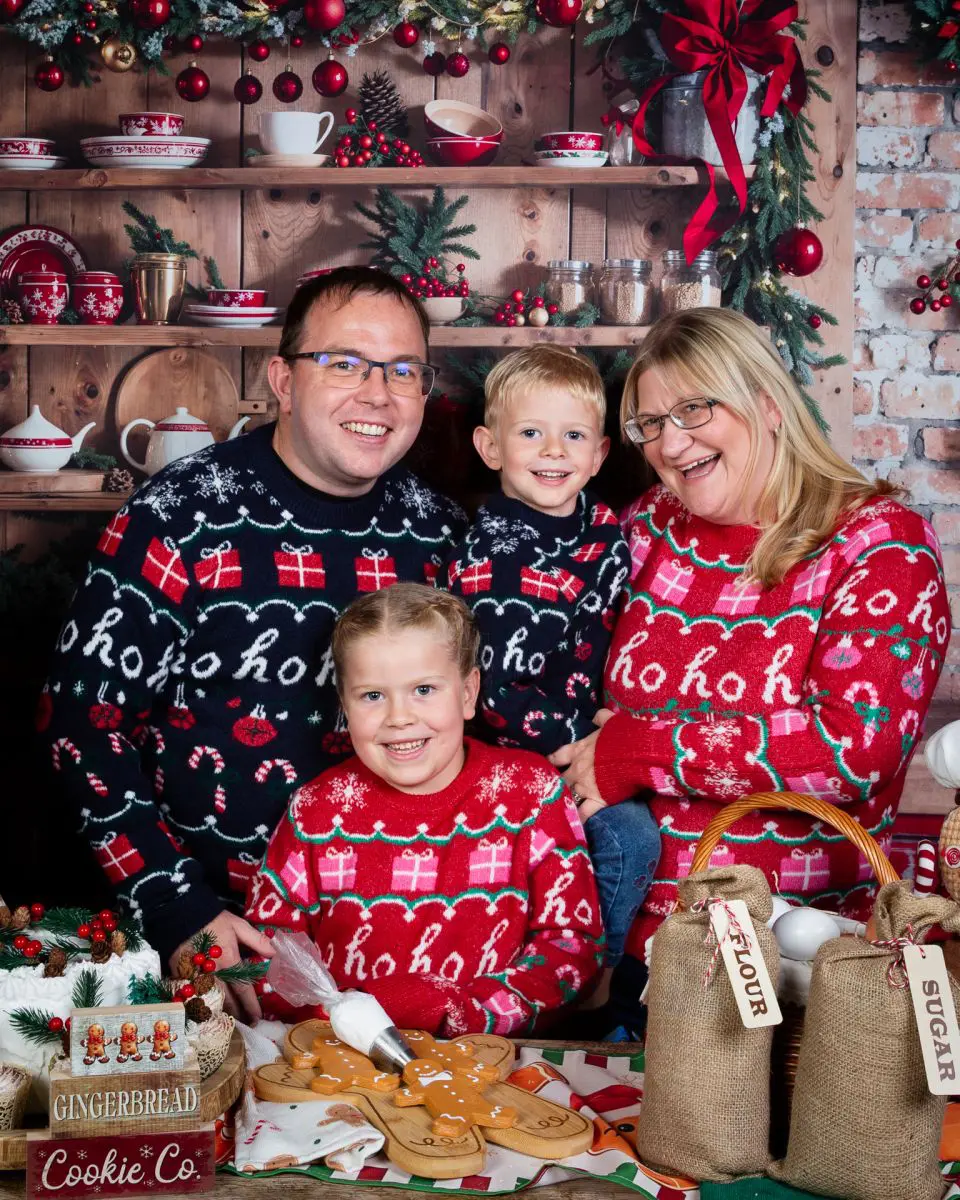 a family pose together and smile in a christmas themed set