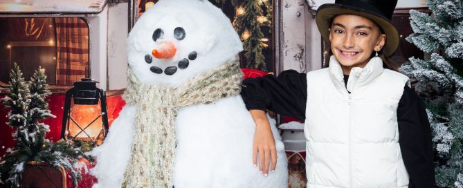 a girl poses with Frosty the giant snowman
