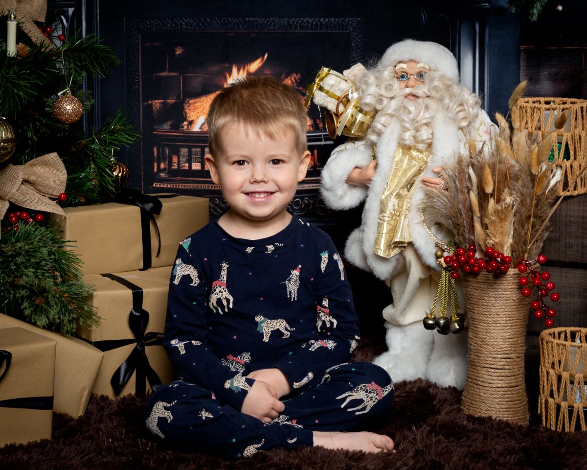 Christmas Photo Shoots West Sussex 2025 a little boy in pyjamas poses in a Fireside themed Christmas set