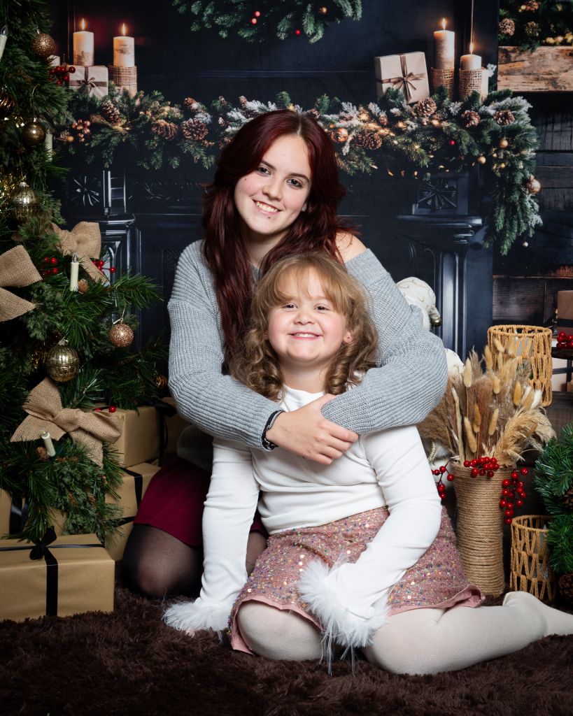 Sisters pose together in a fireplace scene at a photo shoot