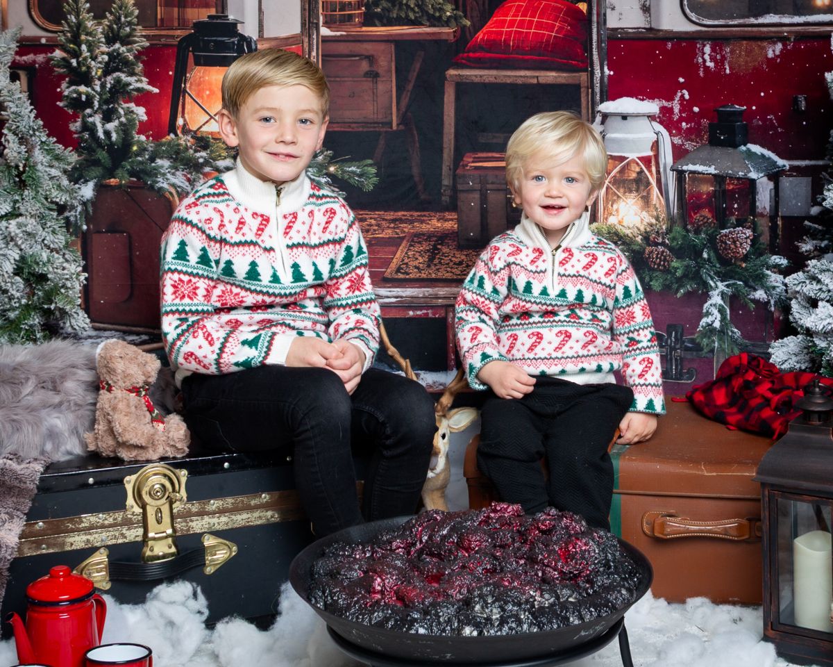 Christmas Photo Shoots West Sussex 2025 two children in matching jumpers pose in a Christmas themed set