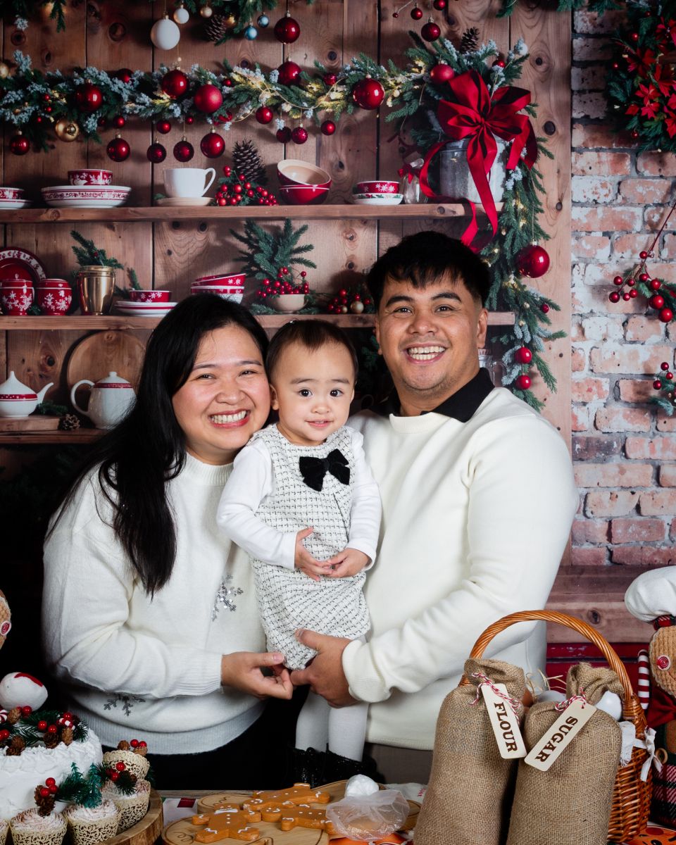 Christmas Photo Shoots West Sussex 2025 a family in matching white jumpers pose in a christmas themed set