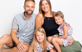A family of mum, dad and two daughters pose for a professional photo shoot