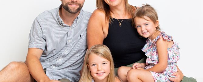 A family of mum, dad and two daughters pose for a professional photo shoot