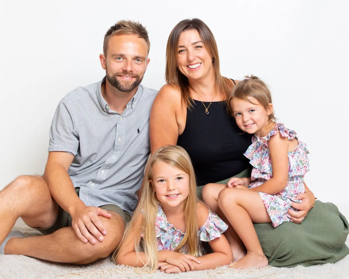 A family of mum, dad and two daughters pose for a professional photo shoot