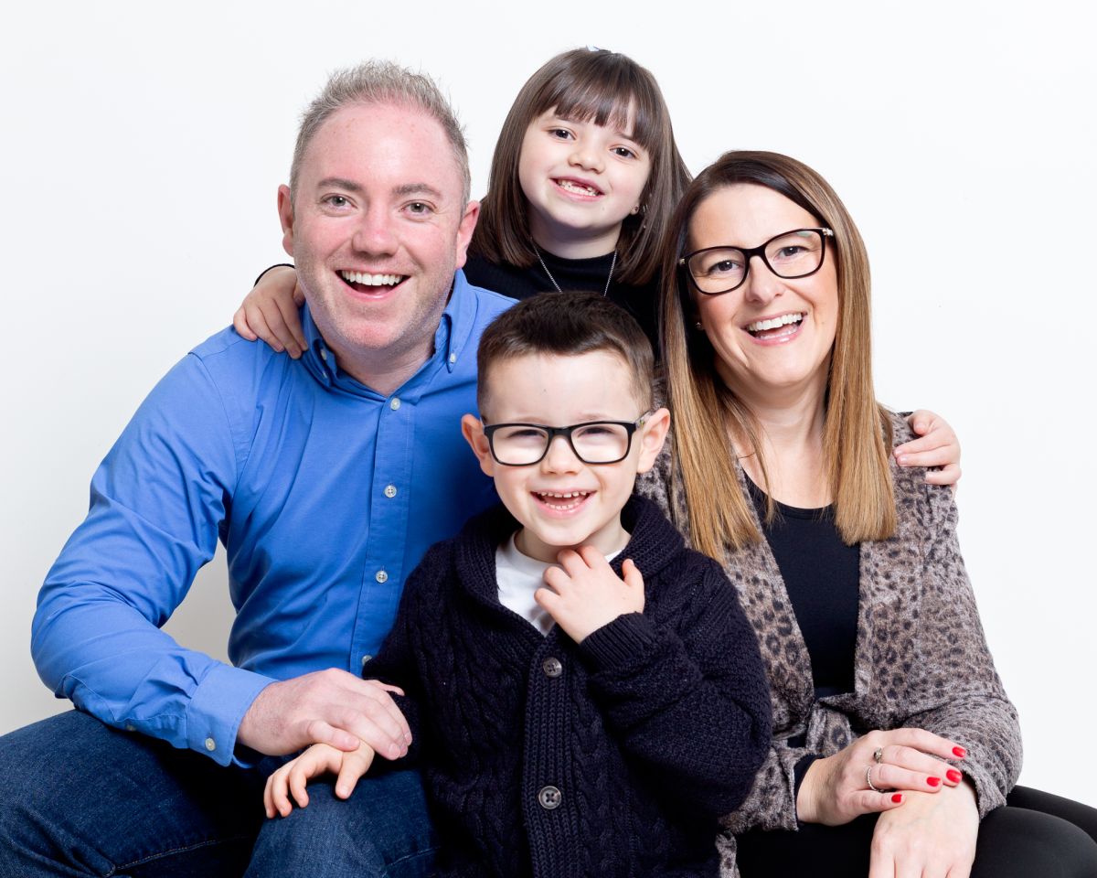 A family of mum, dad and two children pose for a professional photo shoot