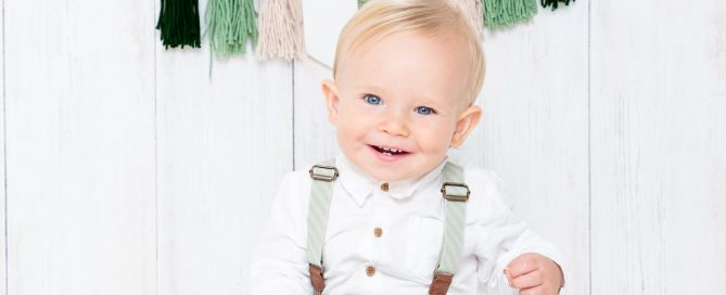 a little boy in a green outfit at his first birthday cake smash shoot