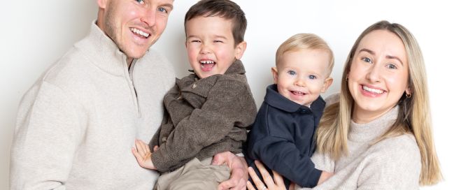 A mum, dad and their two sons laugh at a photo shoot