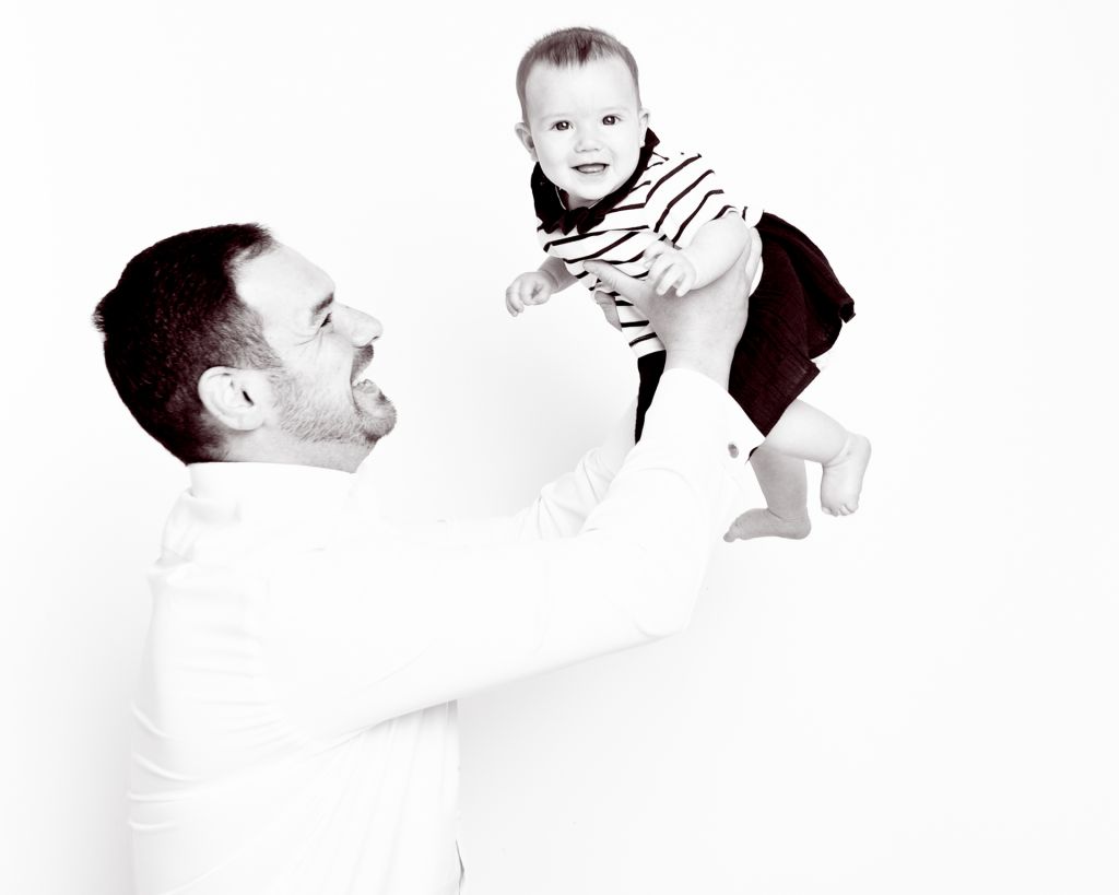 A black and white image of a dad playing with his infant daughter
