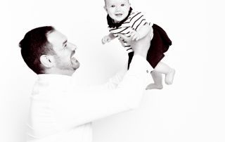 A black and white image of a dad playing with his infant daughter