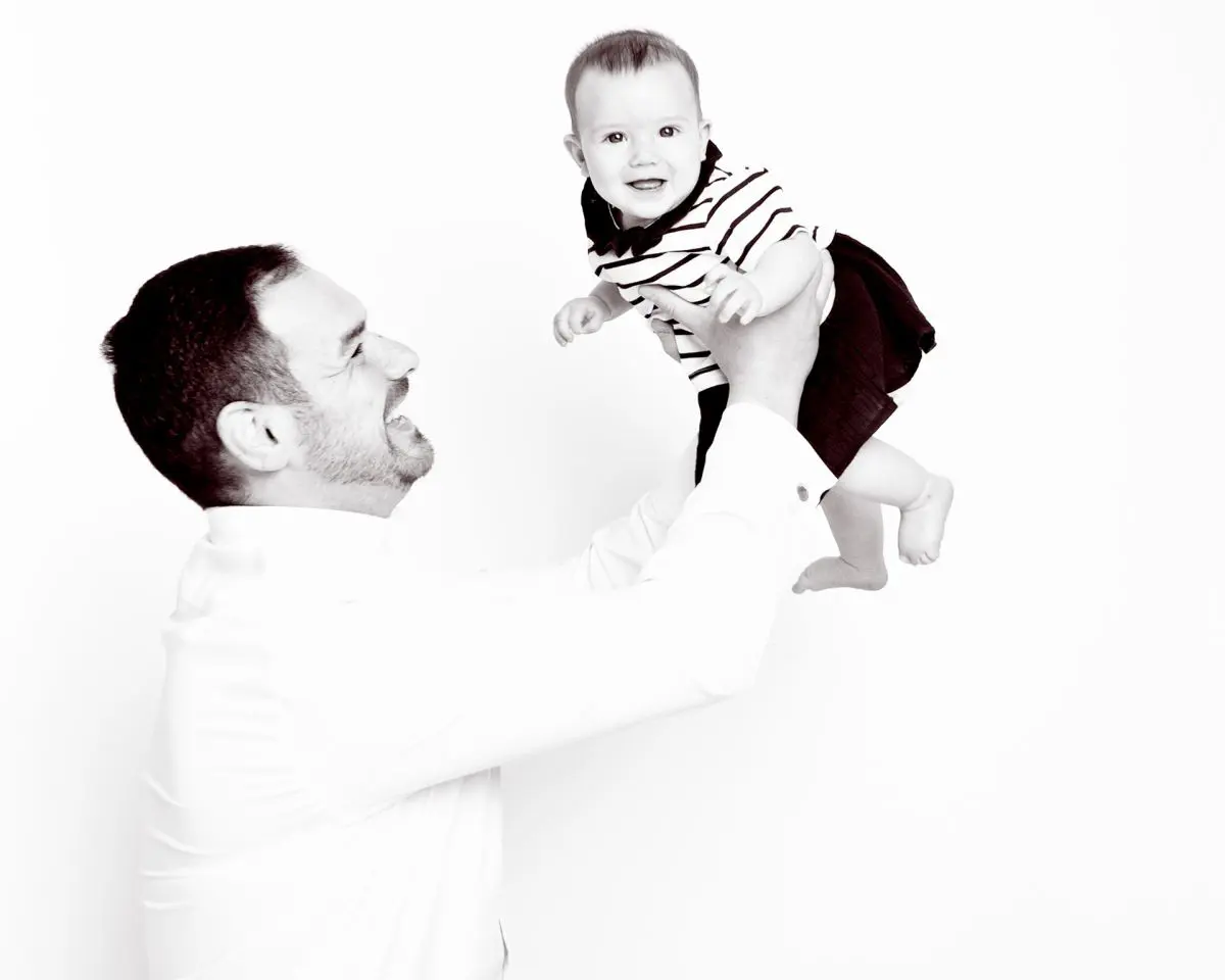 A black and white image of a dad playing with his infant daughter