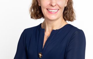 A business headshot of a woman with folded arms and a blue top