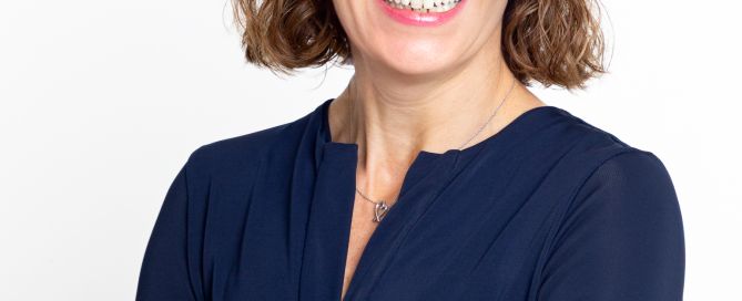 A business headshot of a woman with folded arms and a blue top