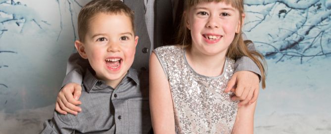 three children pose in smart outfirst for a Christmas photo shoot