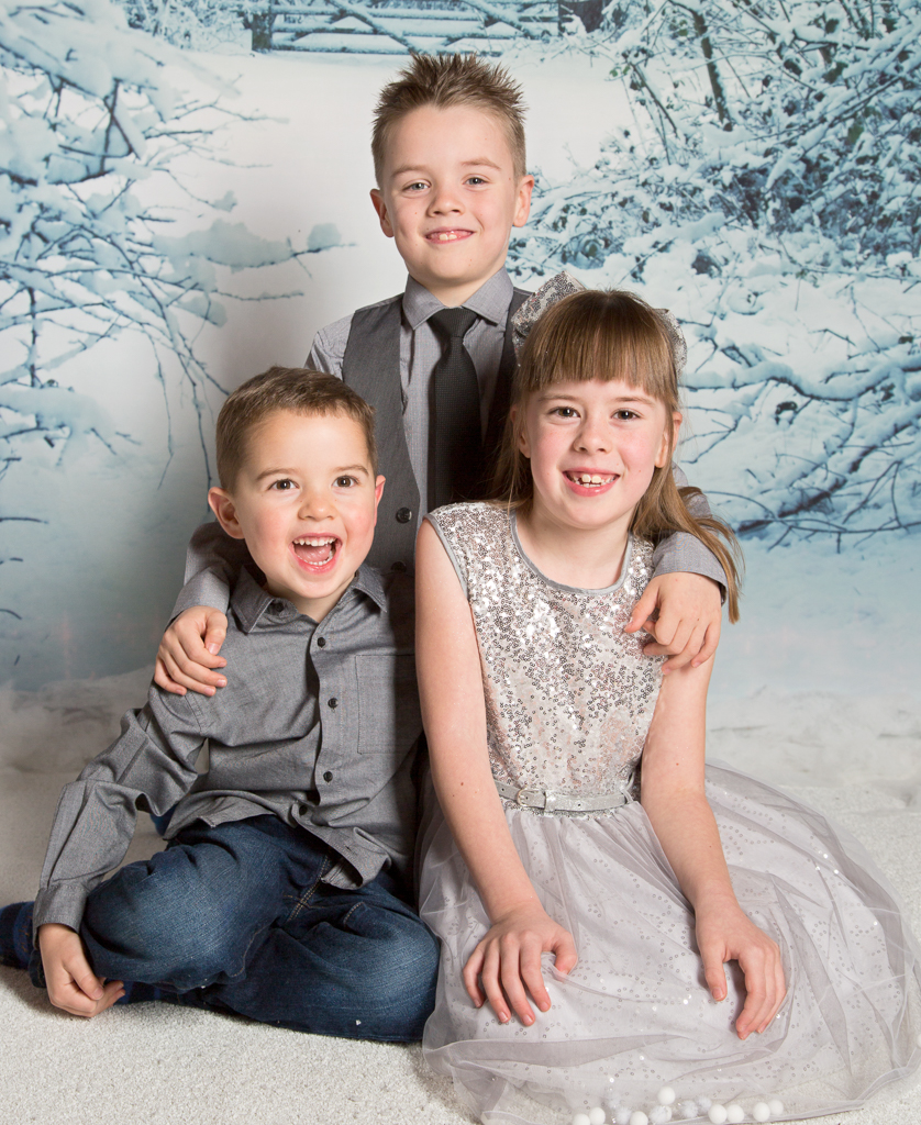 three children pose in smart outfirst for a Christmas photo shoot