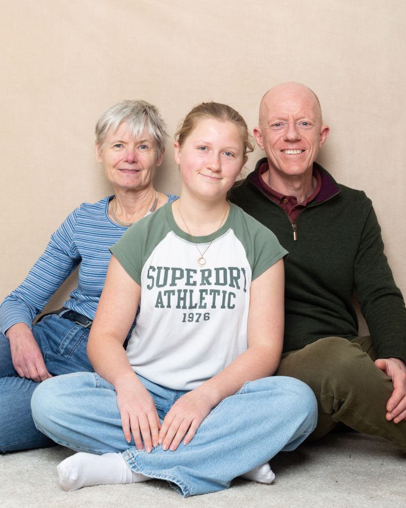 A teenage girl poses in between her parents at a professional portrait shoot