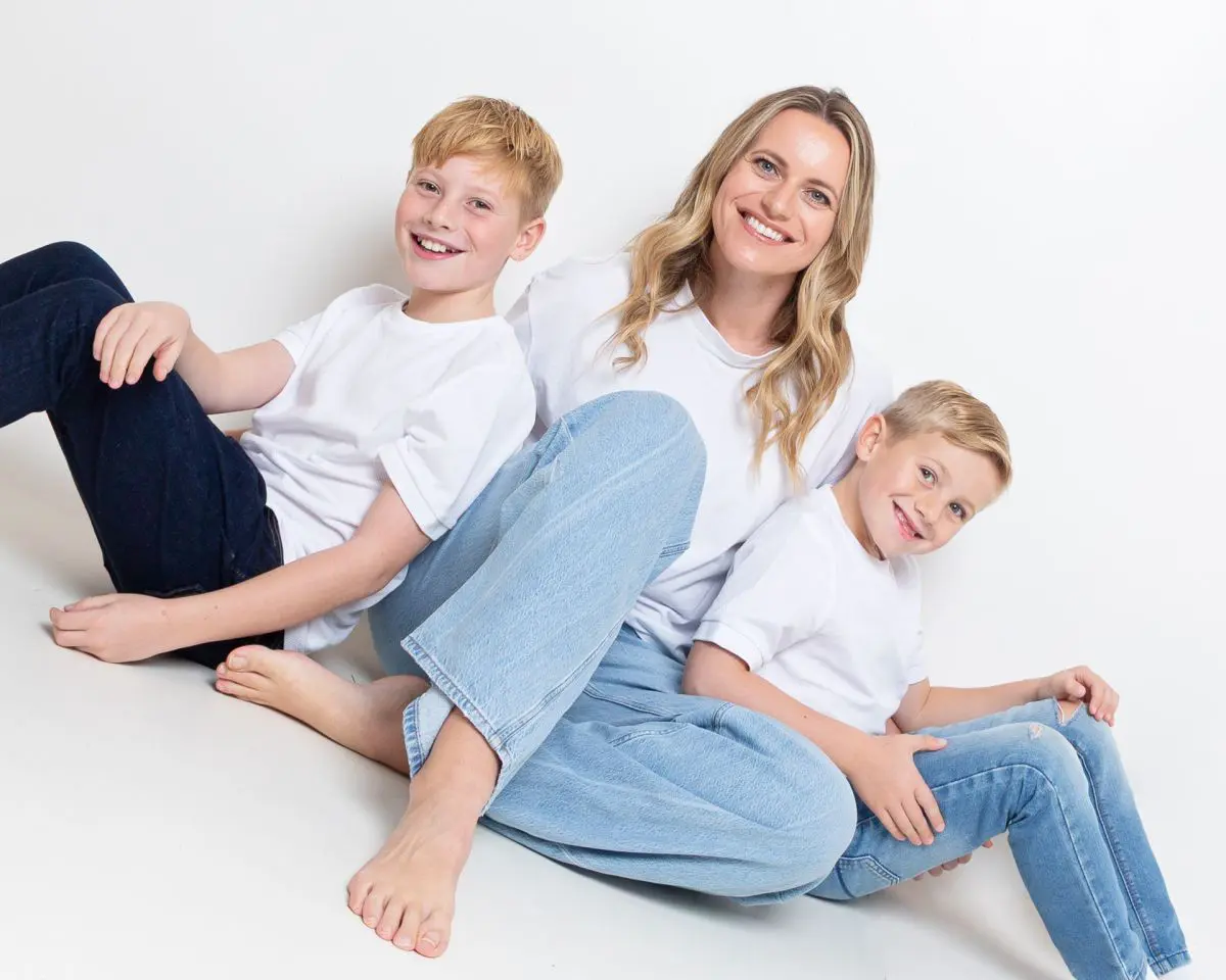 a mum and her two boys pose together in white tshirts and blue jeans