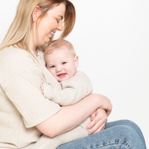 a woman cuddles her son -both dressed in cream