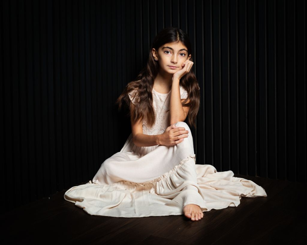 a girl poses seated in a long dress