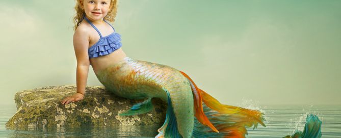 A digital image of a little girl styled as a mermaid sitting on a rock