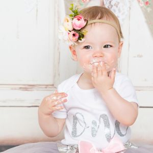 a little girl with icing on her face at a cake smash photo shoot