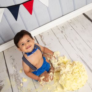 a little boy is very messy at his cake smash photo shoot