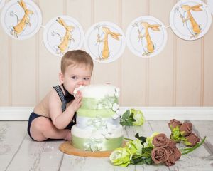 a little boy eating cake at at Nutbrown Hare themed cake smash photo shoot