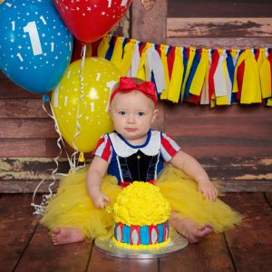a little girl at a Snow White themed cake smash photo shoot