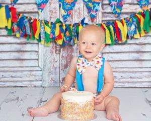 a little boy at a colourful cake smash photo shoot