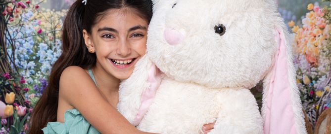 a little girl hugs a giant bunny at an easter photo shoot