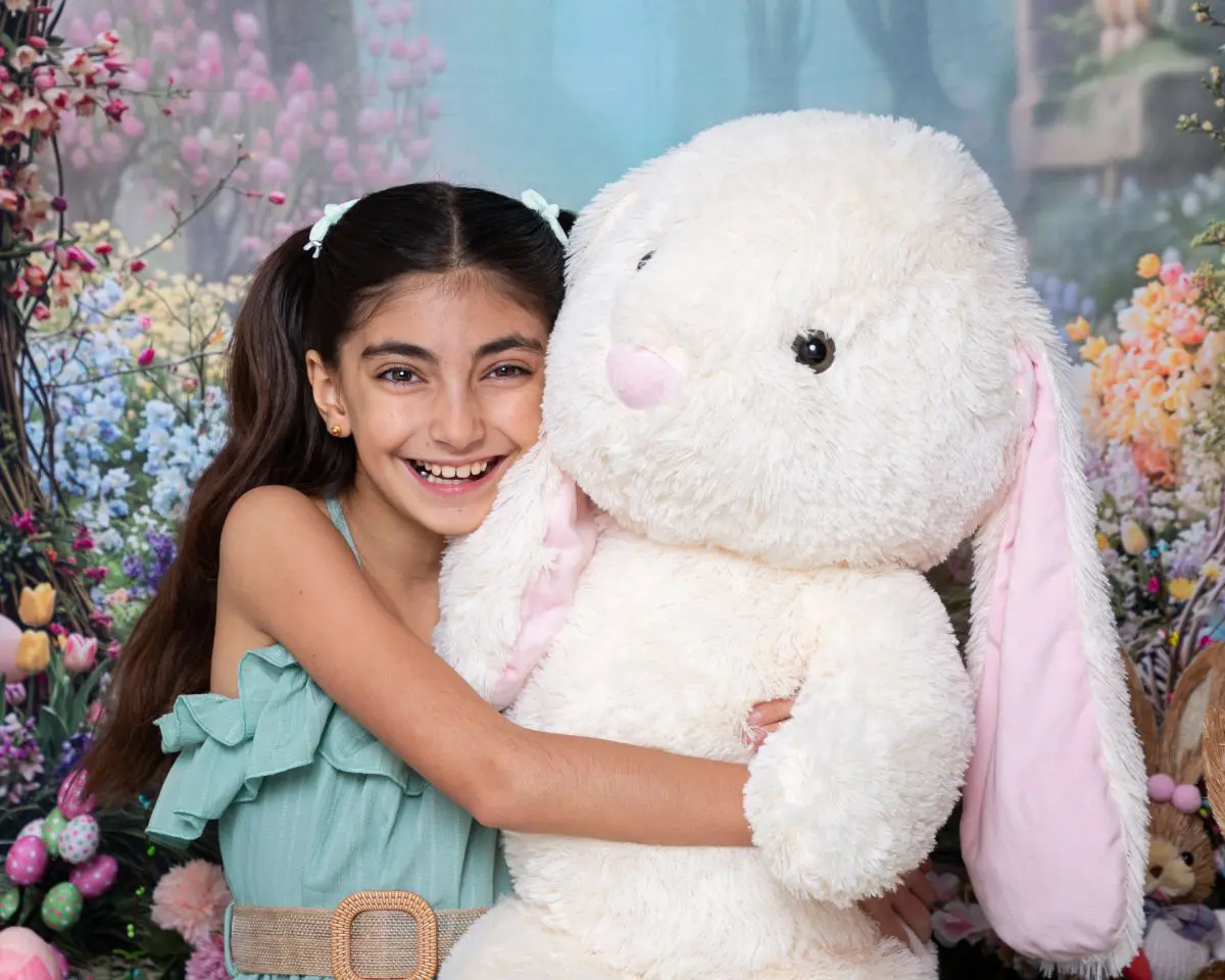 a little girl hugs a giant bunny at an easter photo shoot