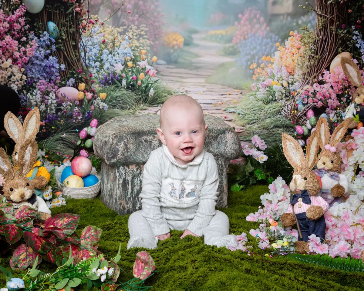 a little boy smiles surrounded by bunnies at an easter mini photo shoot