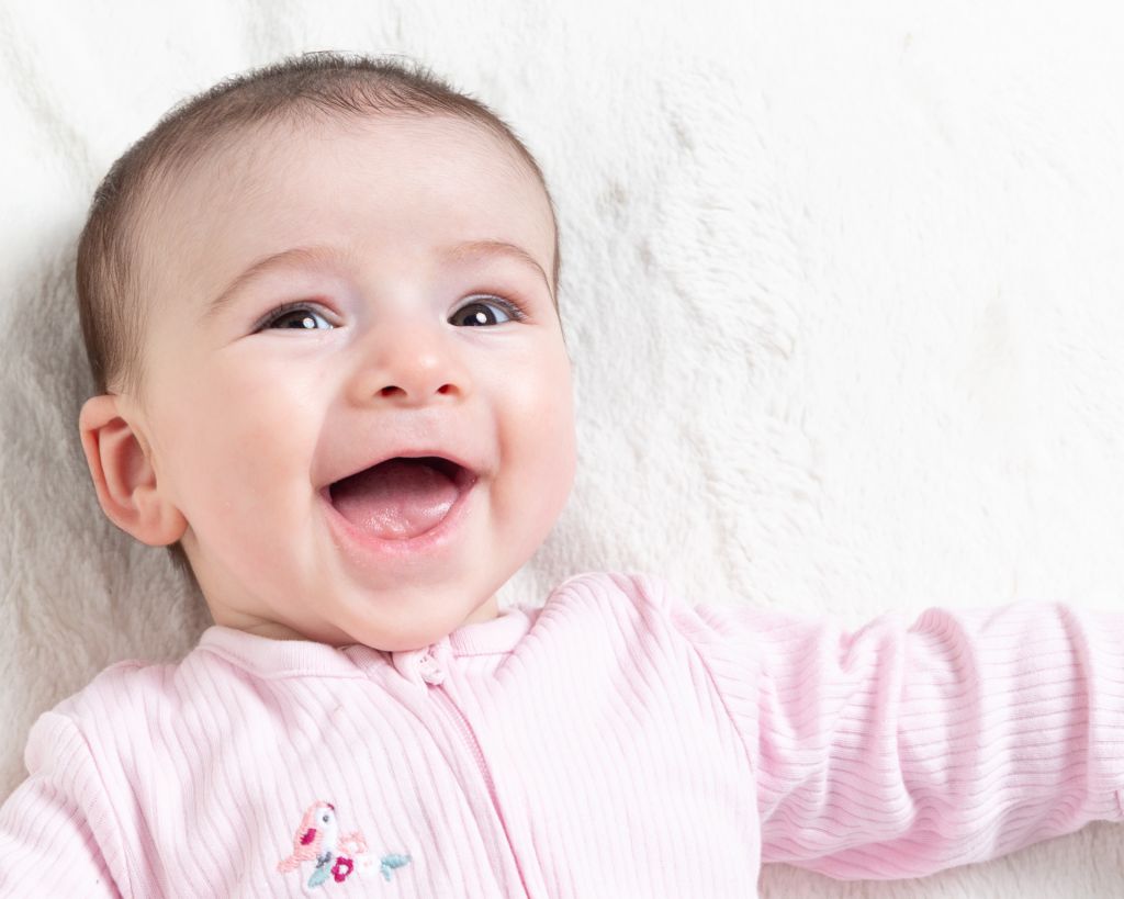 a little girl looks at the camera and smiles for her first photo shoot