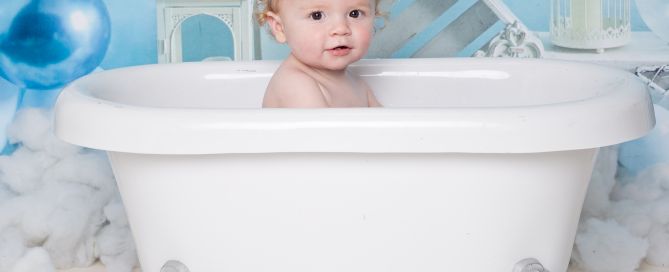 a little boy in a white bath in front of a blue backdrop