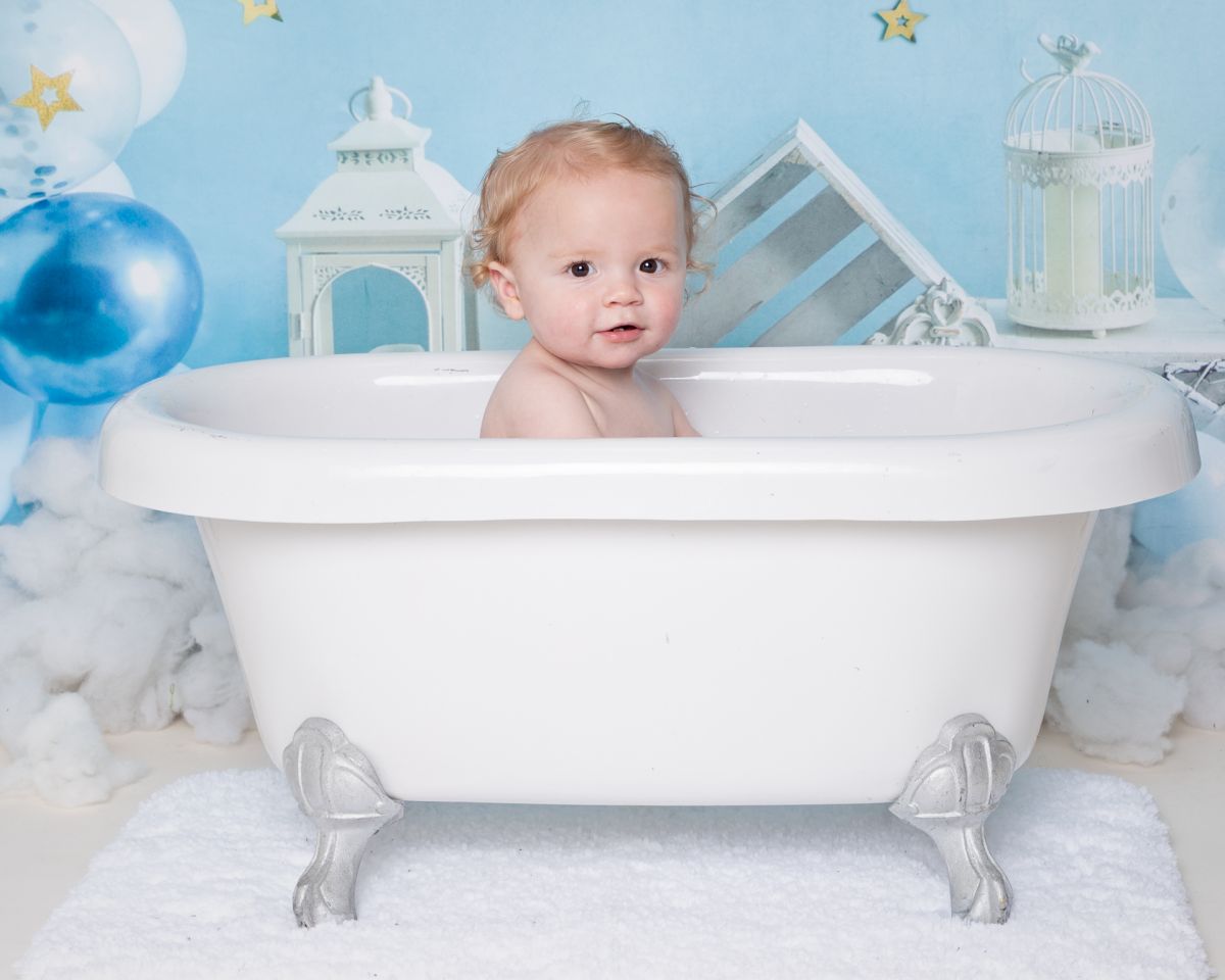 a little boy in a white bath in front of a blue backdrop