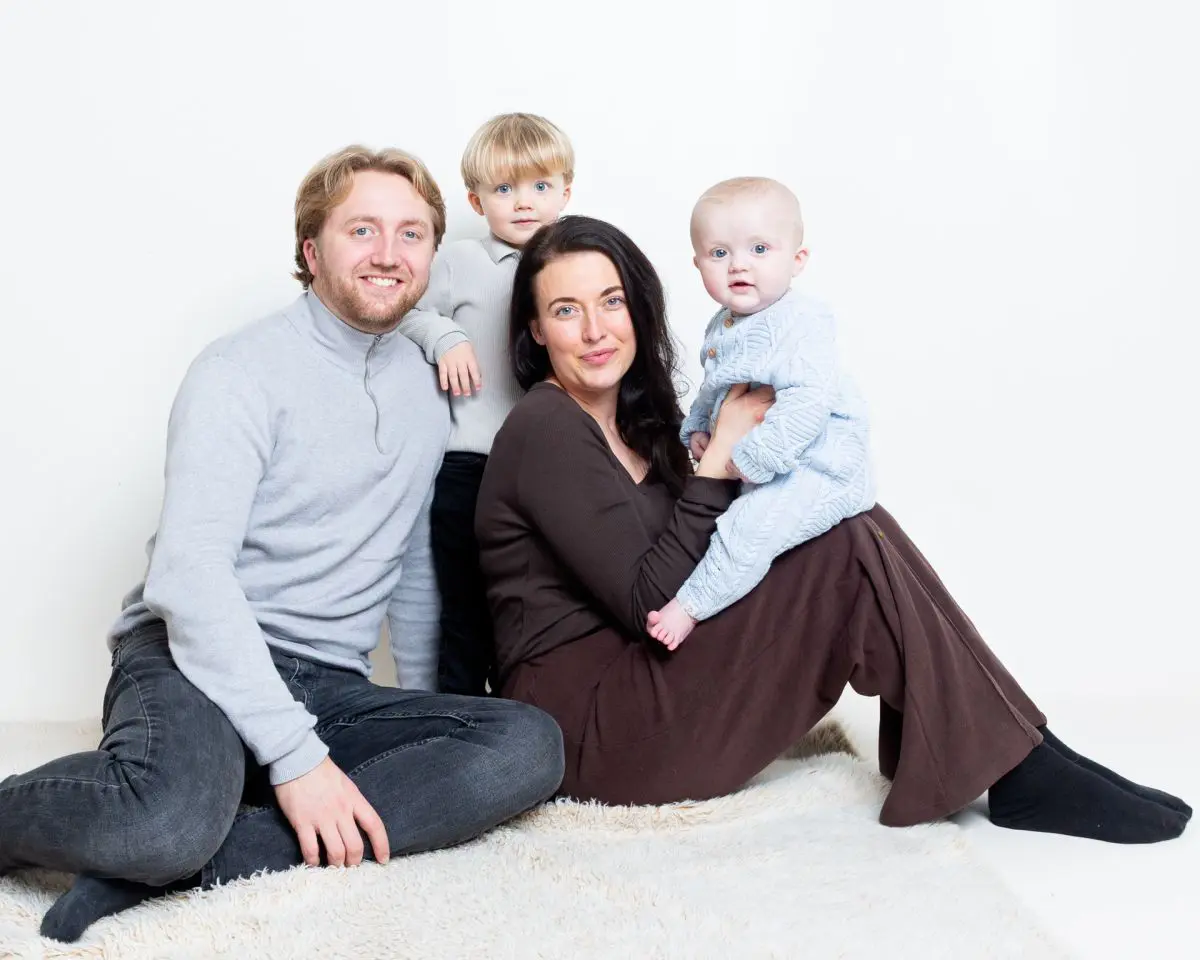 A family of four pose for a photo shoot with their newest family member