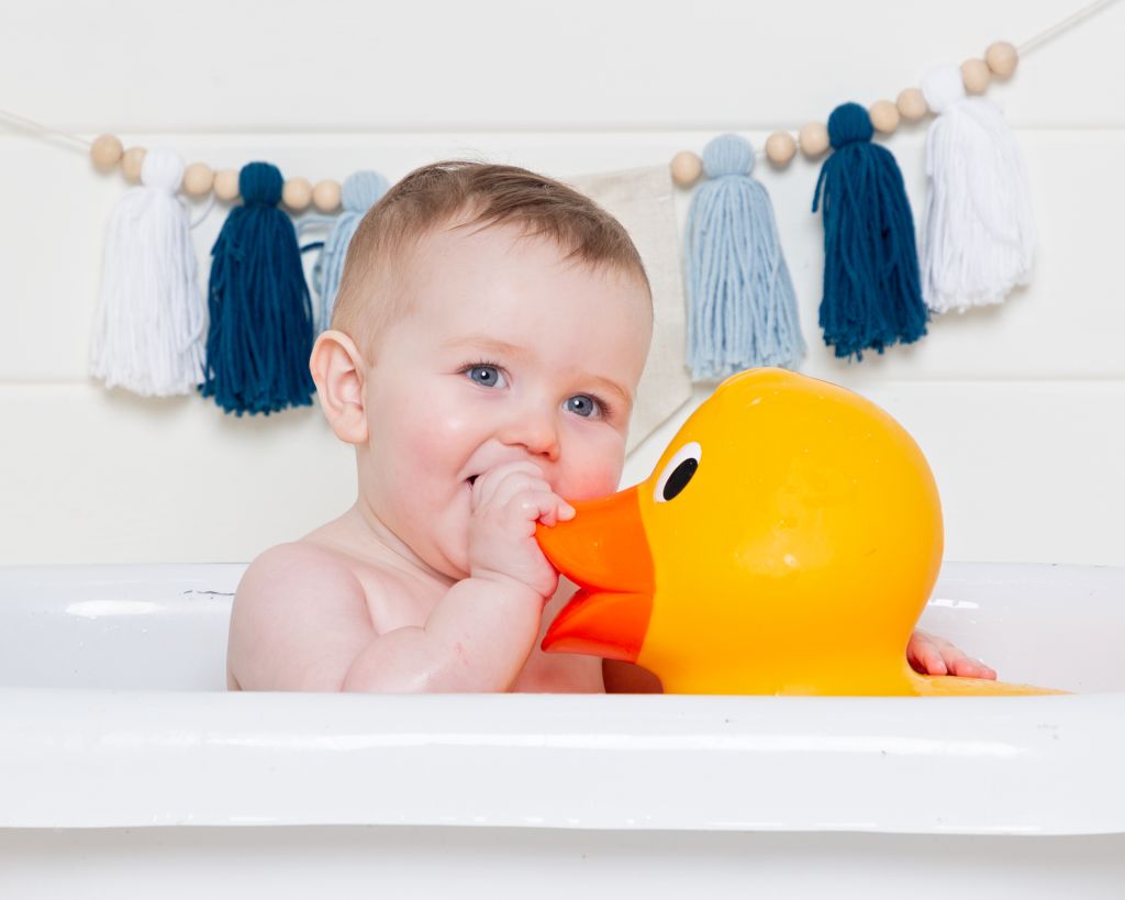 a baby in a bath with a giant rubber duck at a tub splash photo shoot