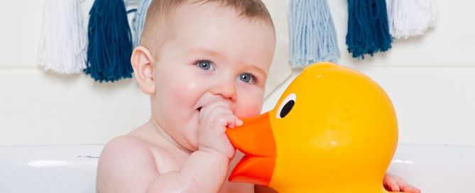 a baby in a bath with a giant rubber duck at a tub splash photo shoot