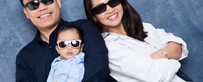a family of three pose in the studio all wearing sunglasses