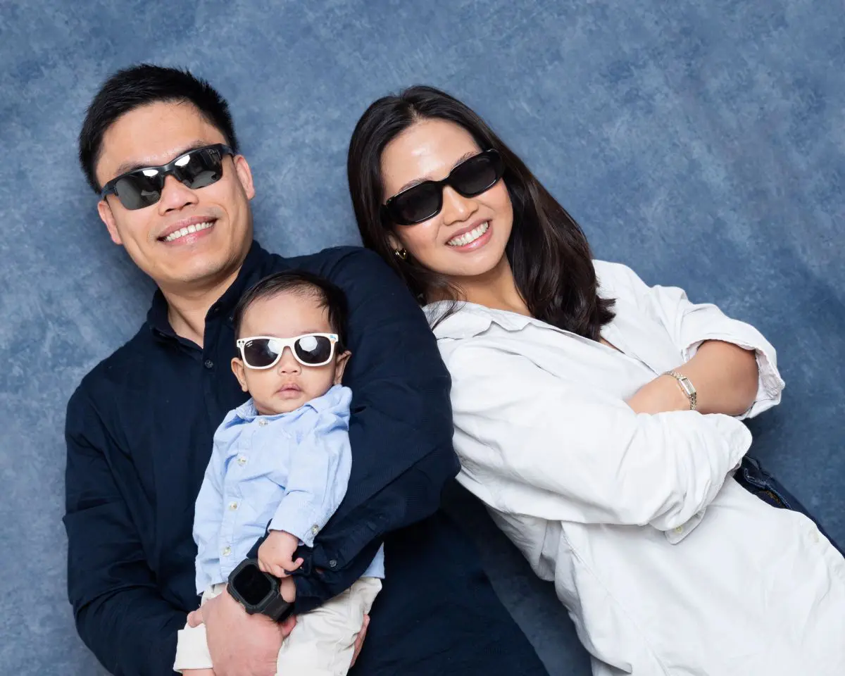 a family of three pose in the studio all wearing sunglasses