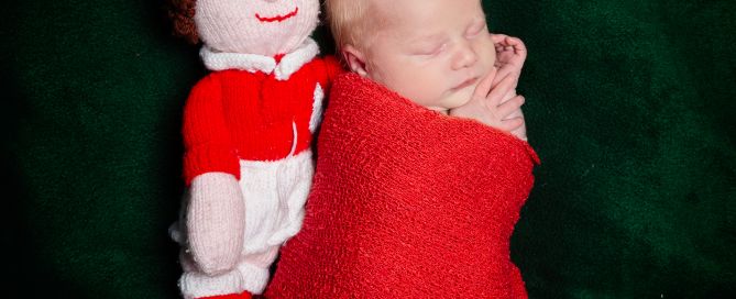 a newborn sleeps next to a handmade footballer toy