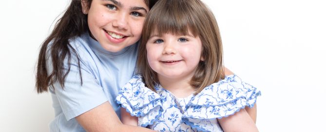 sisters cuddle in the portrait studio both dressed in blue