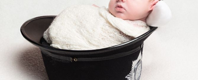 a swaddled baby sleeping in his dad's police helmet