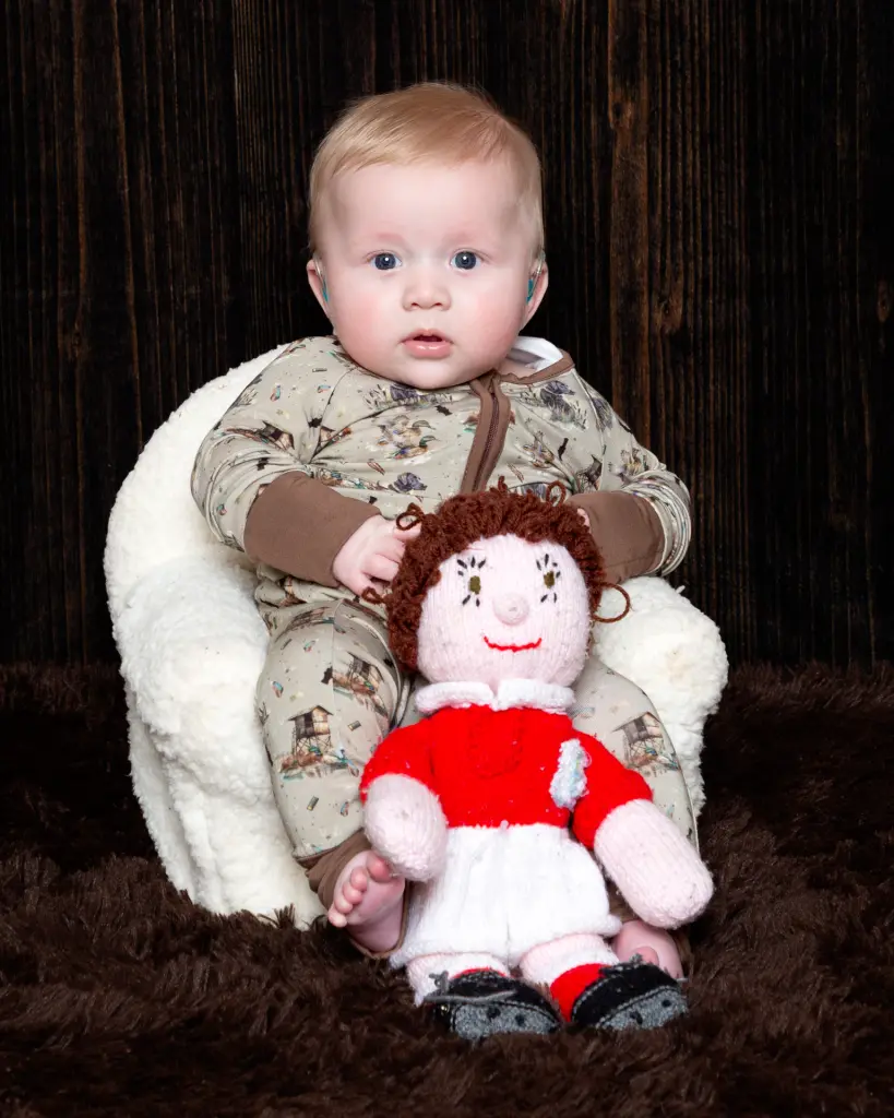 a little boy sits next to his handmade footballer toy